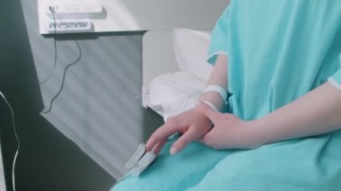 Kemoterapiden sonra yatağa oturup hastanenin penceresine bakan onkolojili genç bir kadın.
