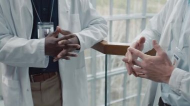 Klinik koridorunda birbirleriyle iletişim kuran çok ırklı tıp çalışanlarının görüntüsü.