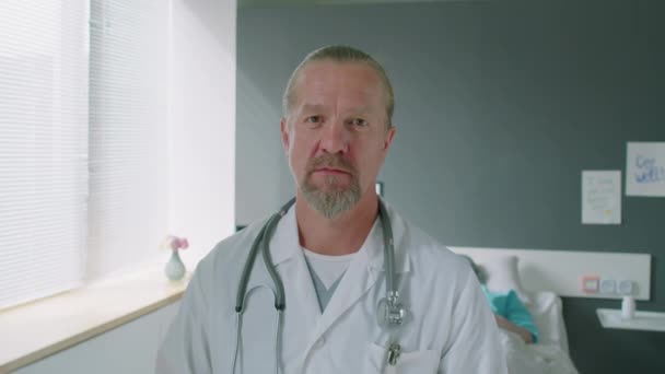 患者のベッドに向かって病棟に立っている間 首の目視鏡を用いた成熟した自信ある医師の肖像 — ストック動画