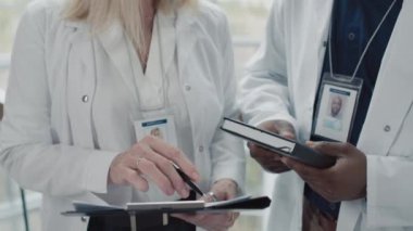 Odada dikilen ve klinikle ilgili notlar alan tıbbi çalışanların kırpılmış görüntüsü.