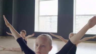 Jimnastik dersinde iki büklüm otururken kollarıyla egzersiz yapan kızları aşağı eğ.