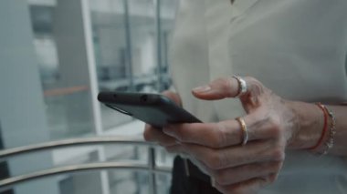 Modern iş merkezindeki asansörle yukarı çıkarken akıllı telefon kullanan bir ofis çalışanının kadın ellerini kapatın.