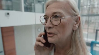 Modern ofis binasında asansöre binerken akıllı telefondan konuşan başarılı bayan girişimciyi kapatın.