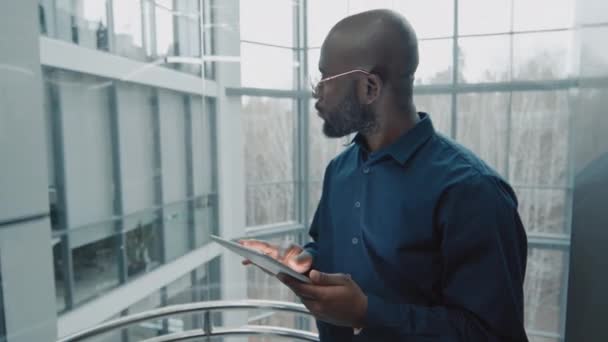 拥有数码平板电脑的非洲裔美国企业家在其现代办公室使用电梯的中景照片 — 图库视频影像