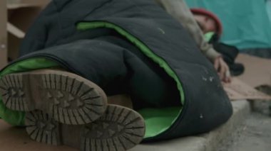Sokakta eski bir battaniyeyle kaplanmış evsiz bir adam cesedi.