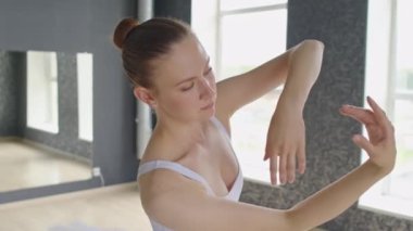 Genç dansçının dans ederken ve kollarını bale stili kaldırırken büyük pencereli stüdyoda antrenman yaparken orta boy bir fotoğrafı.