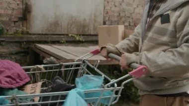 Sokak serserilerinin çöp konteynırlarını açarak sokaktaki hayat için gerekli olan farklı şeyleri ararken çekilmiş görüntüler.
