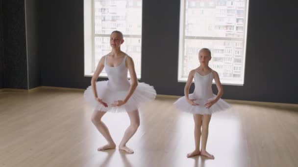 スタジオでレッスン中にバレエスタイルでジャンプする白いチュートスカートとリーツのダンサーの広いショット — ストック動画
