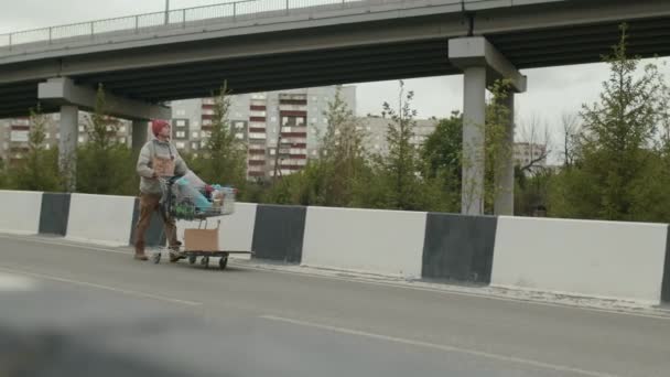 Długie Ujęcie Włóczęgi Jadącej Autostradą Wózkiem Zakupy Nieznanym Miejscu — Wideo stockowe