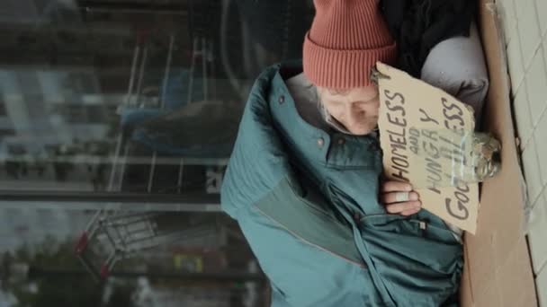 Κάθετη Βολή Αλήτης Κοιμάται Στο Έδαφος Κρατώντας Πινακίδα Άστεγος Και — Αρχείο Βίντεο