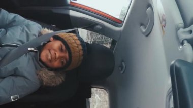 Afro-Amerikan çocuğun kışın biriyle seyahat ederken koltukta oturduğu dikey bir fotoğraf.
