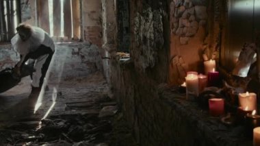 Palyaço kostümlü bir manyağın terk edilmiş duvarları ve yanan mumları olan siyah bir çöp torbasının içinde cesetleri sürüklemesi.