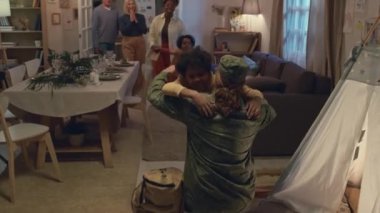 Mutlu aile fertlerini yakından çek ve savaştan sonra eve dönen kamuflaj üniformalı askeri adama sarıl.