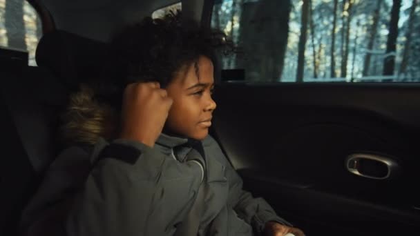 アフリカ系アメリカ人の子供がイヤホンを着て車でどこかに行っている間にビートにぶつかる様子 — ストック動画