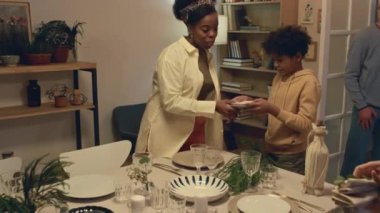 Çok ırklı aile üyeleri önemli bir olayı kutlamaya hazırlanırken tabak ve yemekle şenlik masasına servis yapıyorlar.