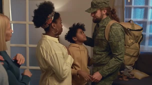 不同文化间家庭中悲伤的成员站在客厅里向离开战场的军人告别的侧影 — 图库视频影像