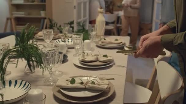 家族の夕食の準備をしている間 お祝いのテーブルにフォークやナイフを置くコーカサス人の男のショットを傾けて — ストック動画