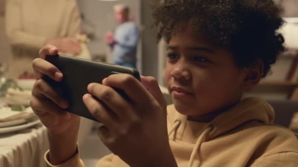 Focus Jongen Spelen Video Game Mobiele Telefoon Terwijl Andere Familieleden — Stockvideo
