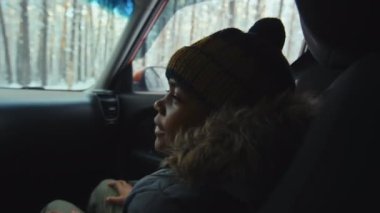 Pencerenin dışında, karlı bir havada arabayla giderken Afrikalı Amerikalı bir çocuğun biriyle konuşmasının yan görüntüsü.
