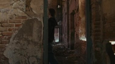 Düşük açılı baltalı çılgın palyaço ürkütücü terk edilmiş bir yerde el feneriyle kadın avcının peşinde koşuyor.