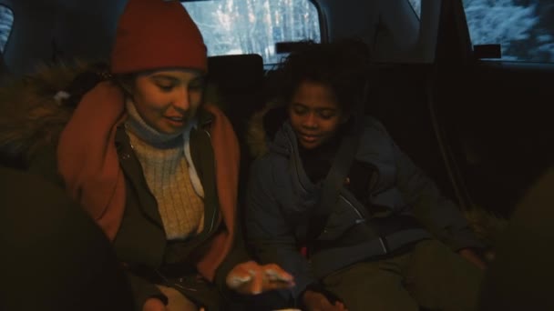 在冬季旅行中 不同文化的母亲和儿子穿着保暖衣服 坐在汽车后座上 使用数码平板电脑 — 图库视频影像