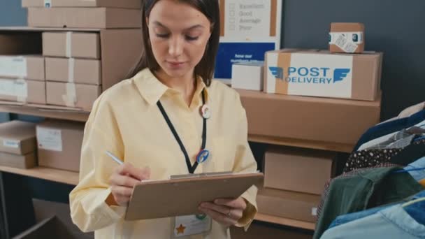 出荷オフィスで働いている間 服を着て情報を書く女性マネージャーの中型ショット — ストック動画