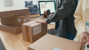 Nakliye paketlerini hazırlarken kadınların depoda kutuları bantlarken çekilmiş görüntüleri.