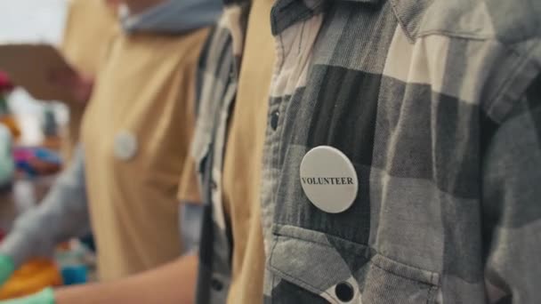 Przycięte Ujęcie Mężczyzny Ubraniach Casual Odznaką Pin Wolontariusz Wybierając Używane — Wideo stockowe