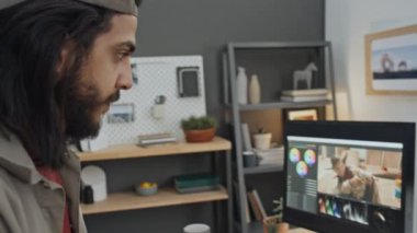 Beyzbol şapkalı genç sakallı Arap grafik tasarımcısının yakın plan çekimi evde duruyor, ergonomik multimedya denetleyici fare kullanarak resim düzenleme yazılımı üzerinde çalışıyor.