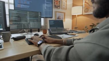 Genç erkek yazılım mühendisinin bilgisayar kodlarını yazarken masada otururken orta omuz üstü pozu, sonra bardak alıp çay içerken.