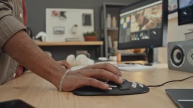 Ofiste ya da evde duran ve profesyonel multimedya denetleyicisi kullanılarak bilgisayar üzerindeki kurgu yazılımında video klipte çalışan isimsiz bir erkek tasarımcının yakın çekim görüntüleri