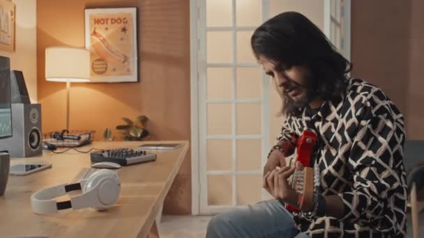 Средний Снимок Молодого Мужчины Гитариста Длинными Волосами Бородой Сидящего Дома — стоковое видео