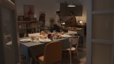 Üç kişilik Yahudi bir aile, anne, baba ve genç kız Hanuka kutlamasına evde hazırlanıyor. Tabaklar ve çatal bıçaklarla dolu masalar, geleneksel yiyeceklerle dolu tabaklar.