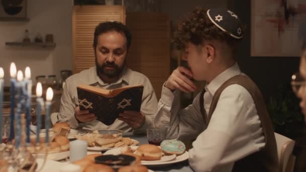 가족과 Hanukkah 식사에 앉아서 거룩한 토라에서 두개골과 아들까지 이야기를 키파에서 — 비디오