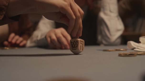 하누카 테이블에 나무로 드레델 장난감을 회전시키는 인식할 유대인 여성의 클로즈업 — 비디오