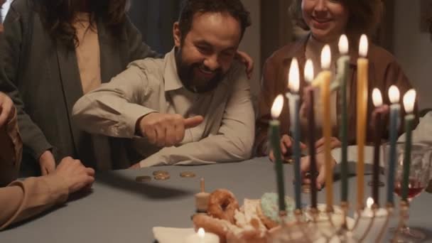 中年のユダヤ人のひげを被ったミディアムショット キッパでは ハヌカの夕食で家族と楽しい伝統的なゲームをプレイし 夢を紡ぎ 応援し 賭けのコイン — ストック動画