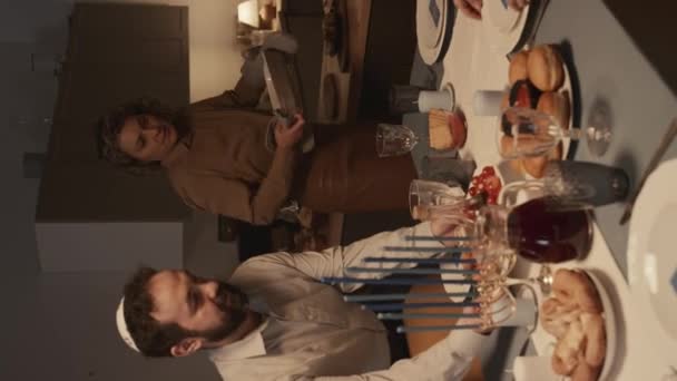 キプパで中年のユダヤ人の夫と妻の垂直ショットは ゲストの到着前に自宅でハヌカの夕食の準備をし テーブルにテーブルにプレートを置く ラッキョート ラッキス ムスムスとキューエル — ストック動画