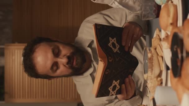 수염을 유대인 아버지의 전통적인 Hanukkah 음식과 테이블에 토라에서 기도를 덮개에 — 비디오