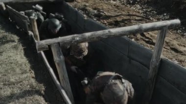 Wehrmacht askerlerinin miğfer taktığı yüksek açılı bir çekim. Tüfekler ihtiyatlı bir şekilde cephe siperleri boyunca ilerliyor. İkinci Dünya Savaşı canlandırması.