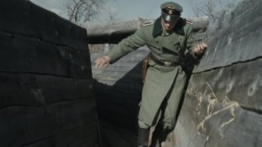 Ağır çekim Alman subayı ön cephe boyunca ilerlerken bir şey bağırırken ve silahını çıkarırken, 2. Dünya Savaşı canlandırması.