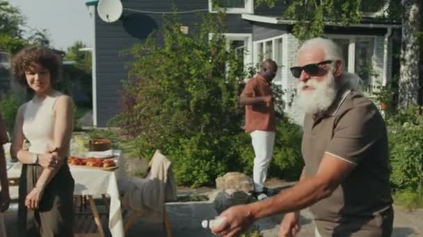 中肖像画快乐的爷爷戴着太阳镜和孩子在后院的派对上打羽毛球 — 图库视频影像