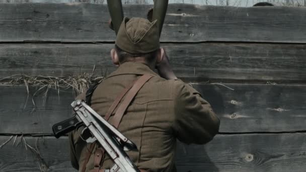 Young Red Army soldier using trench binoculars to spot enemy troop then giving command to his fellow servicemen