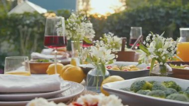 Arka bahçedeki aile yemeği için çiçek ve limonla süslenmiş vejetaryen yiyecek, içecek ve içeceklerle dolu seçici odak noktası.