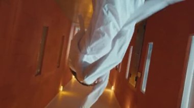 Şizofreni hastası deli gömleği giymiş, psikiyatri hastanesinin koridorunda dans eden adamın dönüşümlü fotoğrafı.