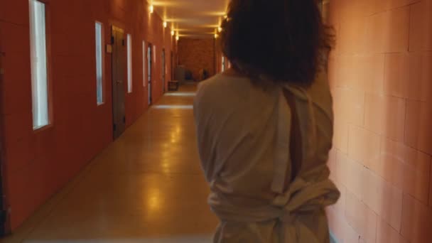 身穿紧身衣 无法辨认的精神病患者在收容所走廊行走时的后视镜镜头 — 图库视频影像