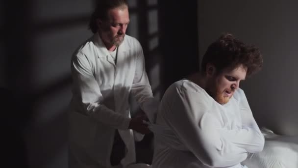 Зрелый Врач Мужчина Завязывает Рукава Смирительной Рубашки Сдержать Жестокого Пациента — стоковое видео