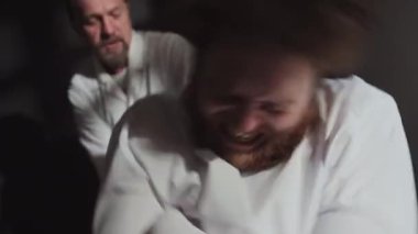 Doktorun deli gömleği kollarını bağlarken ve hastayı akli dengesizlikle yatıştırırken yakın plan fotoğrafı.