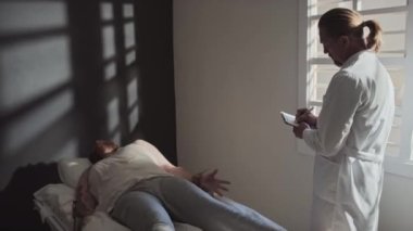 Profesyonel psikiyatrist koğuşta zihinsel bozukluğu olan hastalarla ilgileniyor ve tıbbi kayıtlara not alıyor.