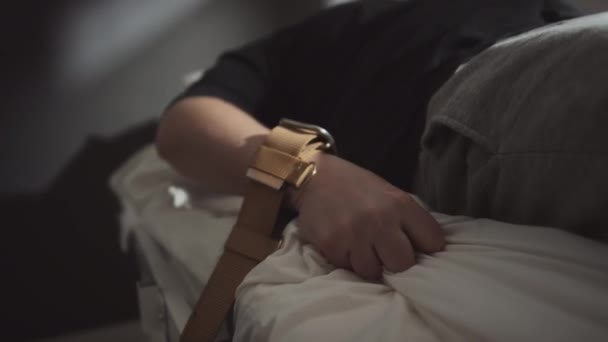 発作に苦しむ茶色のベルトで病院のベッドに縛られた腕を持つ精神障害を持つ患者の選択的な焦点ショット — ストック動画