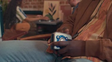 Seçici odak noktası kulaklık takan genç Afrikalı Amerikalı gecekonducuların kişisel stereo müzik eşliğinde sandalyede oturması.